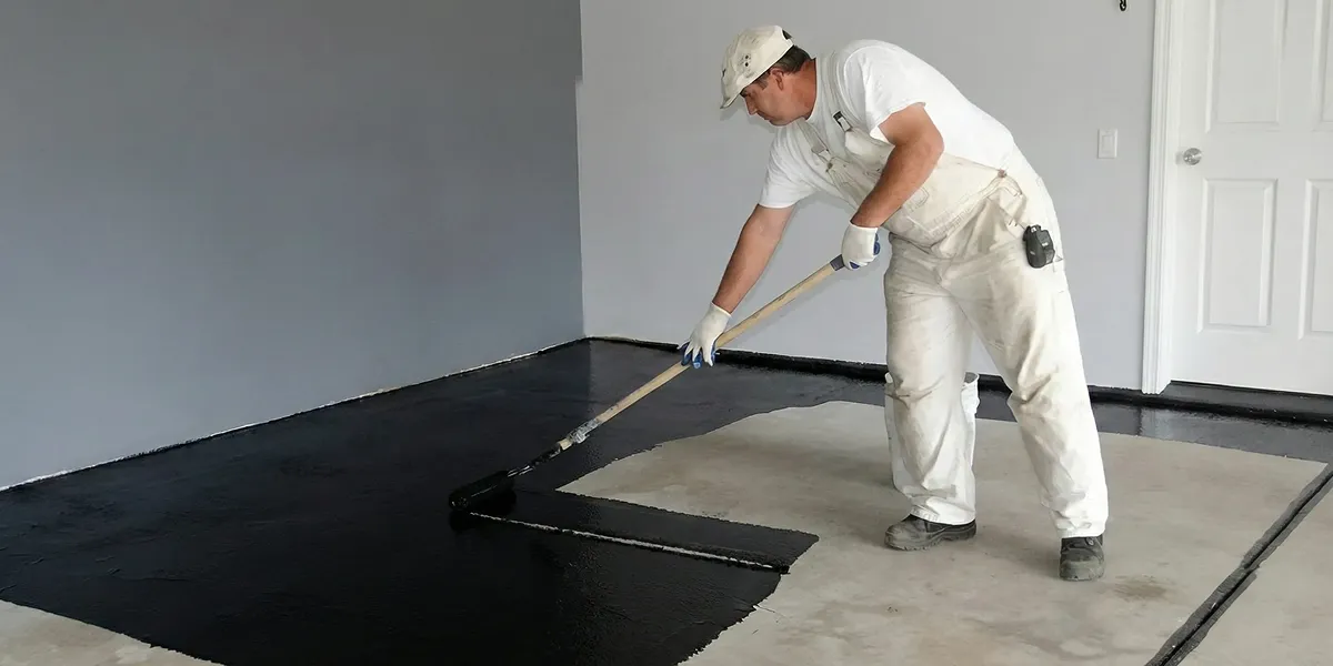 basement waterproofing professional applying waterproof coating to protect a basement floor in Pittsburgh, PA