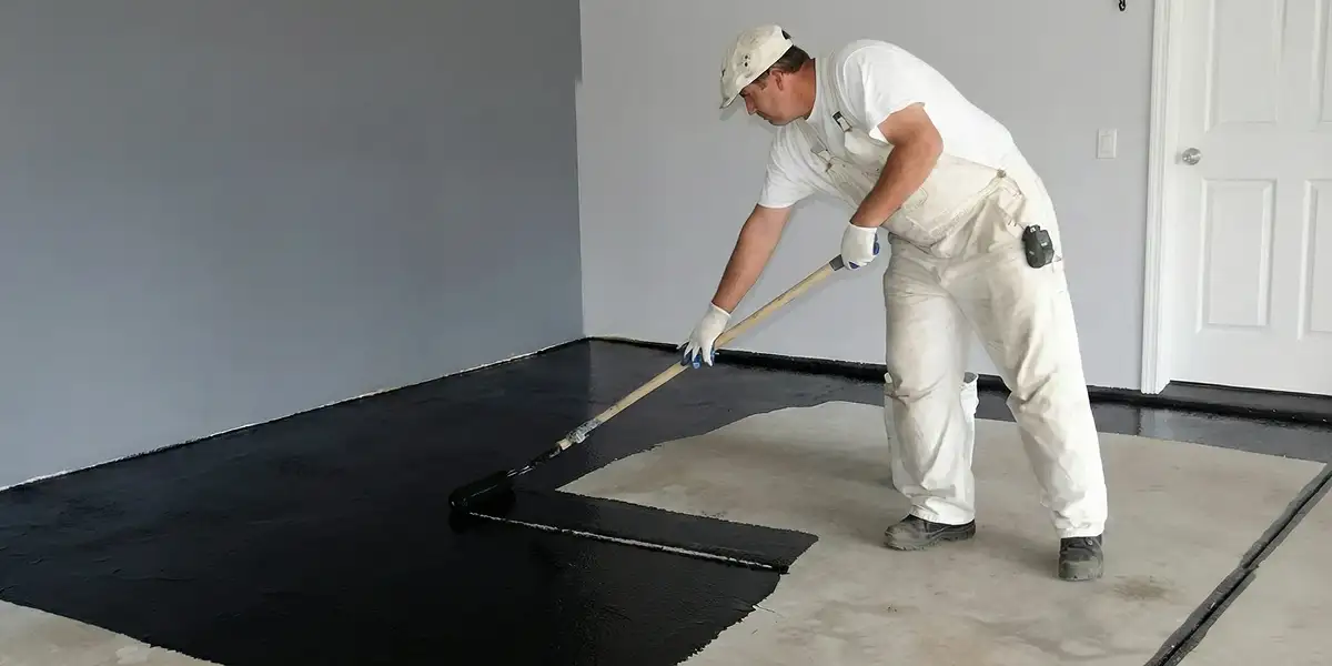 basement waterproofing professional applying waterproof coating to protect a basement floor in Pittsburgh, PA
